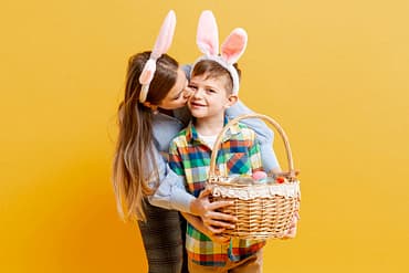 Mãe e filho com tiara de orelhas de coelho da páscoa, ambos segurando uma cesta de presente de páscoa