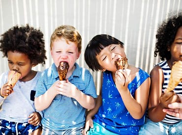 quatro crianças sentadas comendo sorvete na casquinha representando ideias de brindes para o dia das crianças