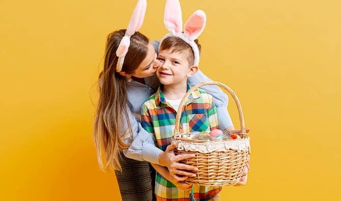 Mãe e filho com tiara de orelhas de coelho da páscoa, ambos segurando uma cesta de presente de páscoa