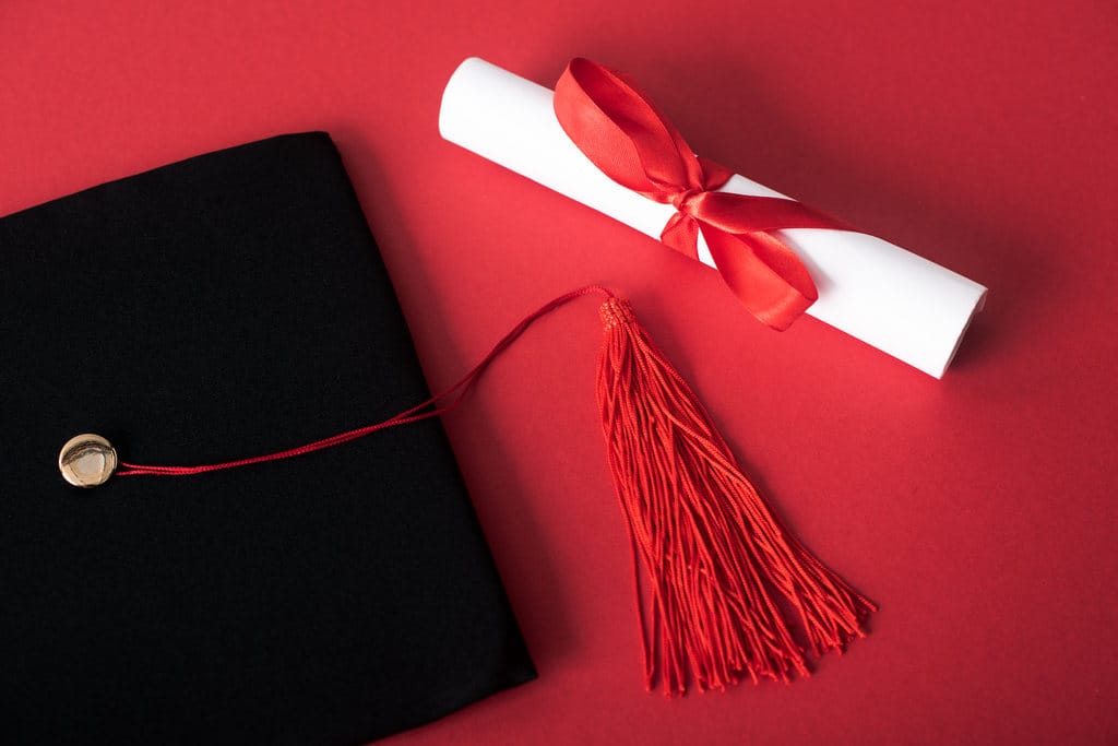 Simbolizando brindes para formatura de cursos diversos: Capelo (chapéu de formatura) e diploma enrolado estilo pergaminho com laço vermelho