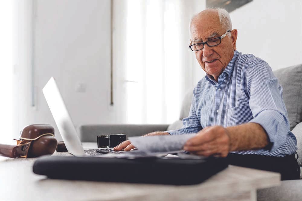 Idoso usando notebook, simbolizando comprar lembrancinhas para idosos online
