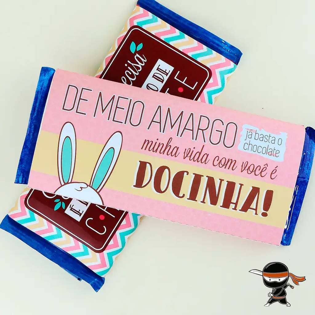 Duas barras de chocolate, uma sobre a outra. Na embalagem da barra de cima, há a ilustração de orelhas de coelho e a mensagem personalizada: "De meio amargo, já basta o chocolate. Minha vida com você é docinha"