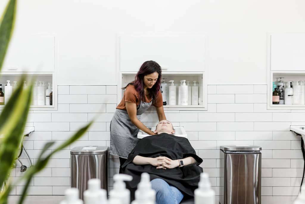 Em um salão de beleza, cabeleireira lavando cabelo de cliente